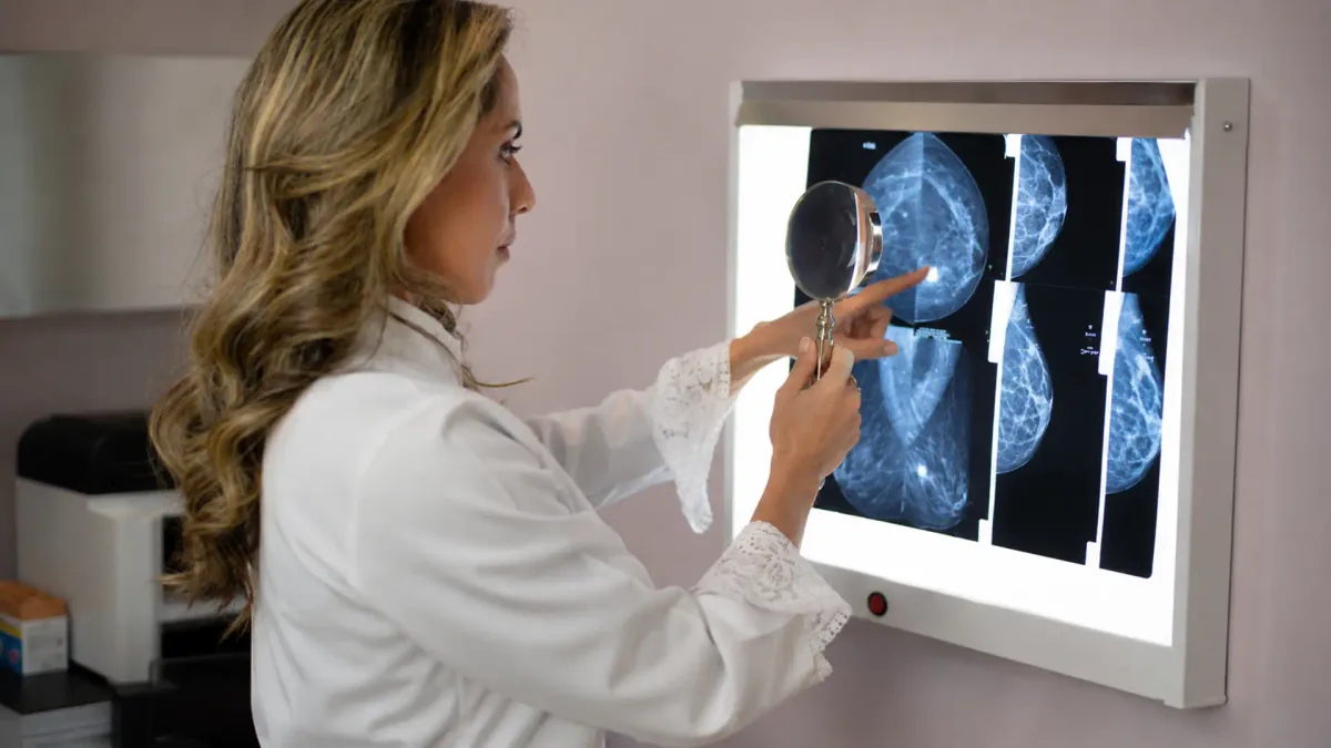 Médica examina imagens de mamografia no negatoscópio com o auxílio de uma lupa