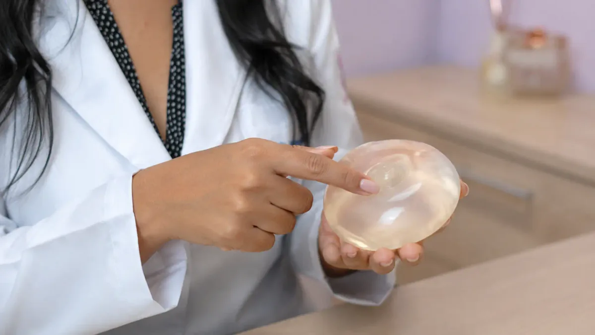 Médica segura um implante mamário de silicone durante orientação em consultório
