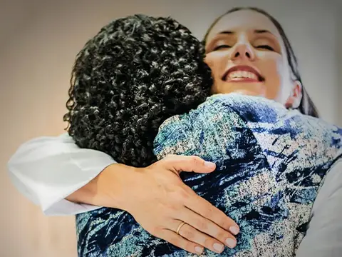 Abraço entre profissional e paciente no acolhimento da consulta
